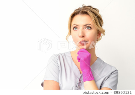 Young caucasian female doctor wearing gloves thoughtful looking away isolated on white background Young caucasian female doctor wearing gloves thoughtful looking away isolated on white background 89893121