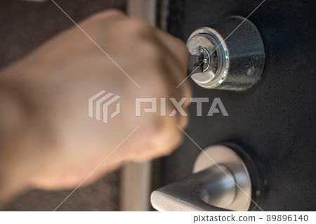 Hand to insert the key into the keyhole 89896140