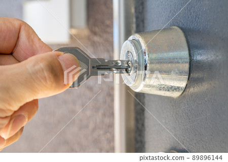 Hand to insert the key into the keyhole 89896144