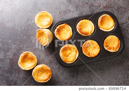 Queijadas or Queijadinhas, little Portuguese cheesecakes made with Queijo Fresco close-up in a baking dish. Horizontal top view Queijadas or Queijadinhas, little Portuguese cheesecakes made with Queijo Fresco close-up in a baking dish. Horizontal top view 89896714
