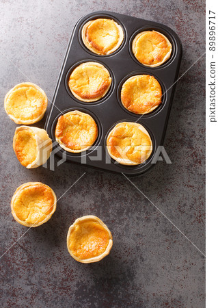 Freshly baked sweet Tarts Queijadas close-up in a baking dish. vertical top view Freshly baked sweet Tarts Queijadas close-up in a baking dish. vertical top view 89896717