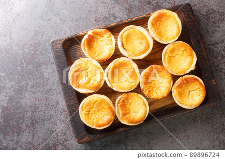 Tasty Portuguese mini Tarts Queijadas are a sweet, creamy, traditional dessert close-up on a wooden tray. Horizontal top view Tasty Portuguese mini Tarts Queijadas are a sweet, creamy, traditional dessert close-up on a wooden tray. Horizontal top view 89896724