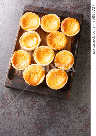 Queijadas de Sintra are one of the most traditional and signature Portuguese pastries close-up on a wooden tray. Vertical top view Queijadas de Sintra are one of the most traditional and signature Portuguese pastries close-up on a wooden tray. Vertical top view 89896727