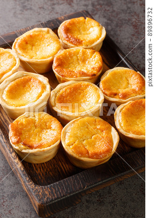 Queijadas Portuguese Cheesecake Tarts close-up on a wooden tray. Vertical 89896732