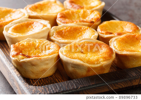Queijadas de Sintra are sweet cheese tarts with a hint of cinnamon close-up on a wooden tray. Horizontal Queijadas de Sintra are sweet cheese tarts with a hint of cinnamon close-up on a wooden tray. Horizontal 89896733