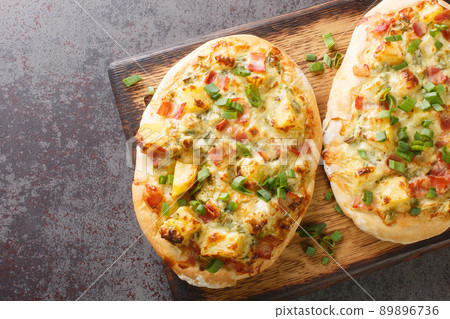 Open pie with cheese, potatoes, onions and bacon close-up on a wooden board. horizontal top view Open pie with cheese, potatoes, onions and bacon close-up on a wooden board. horizontal top view 89896736