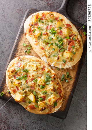 German pizza Swabian Dinnete with potatoes, onions and bacon close-up on a wooden board. vertical top view German pizza Swabian Dinnete with potatoes, onions and bacon close-up on a wooden board. vertical top view 89896738