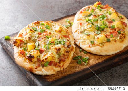 Traditional German pizza with cheese, potatoes, onions and bacon close-up on a wooden board. horizontal Traditional German pizza with cheese, potatoes, onions and bacon close-up on a wooden board. horizontal 89896740