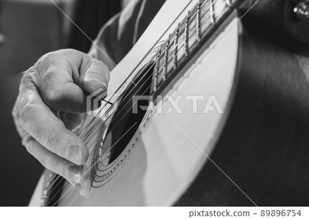 Close-up hands and acoustic guitar. Cropped monochrome portrait of man, rock musician playing guitar isolated on light background. Concept of music, style, art Close-up hands and acoustic guitar. Cropped monochrome portrait of man, rock musician playing guitar isolated on light background. Concept of music, style, art 89896754