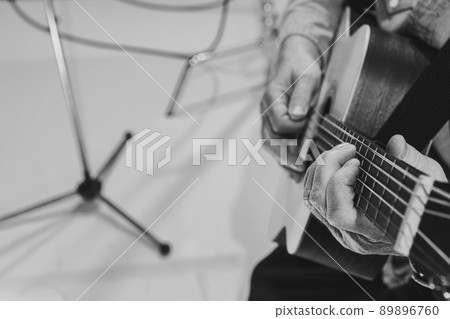 Close-up hands and acoustic guitar. Cropped monochrome portrait of man, rock musician playing guitar isolated on light background. Concept of music, style, art Close-up hands and acoustic guitar. Cropped monochrome portrait of man, rock musician playing guitar isolated on light background. Concept of music, style, art 89896760