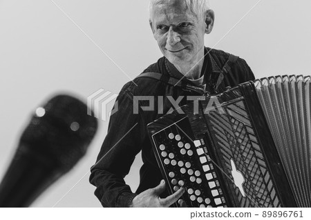 Monochrome portrait of seniot man, retro musician playing the accordion isolated on white background. Concept of art, music, style, older generation, vintage 89896761