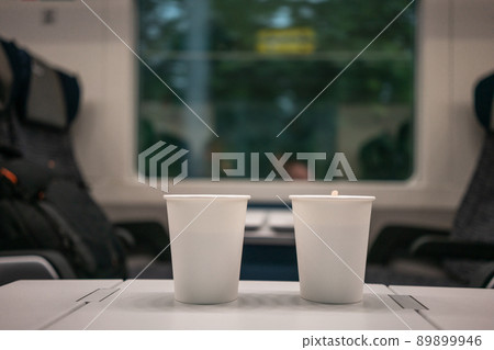 Two white disposable paper cups stand against the background of a window on the train. travel in Europe 89899946