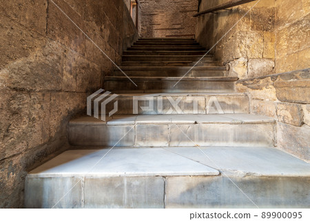 Old narrow stone staircase lending with bricks wall 89900095