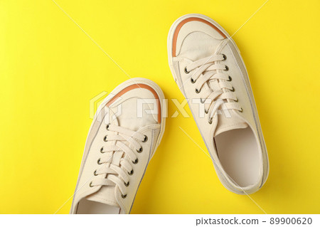 Pair of beige sneakers on yellow background Pair of beige sneakers on yellow background 89900620