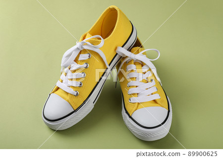 Pair of yellow sneakers on green background Pair of yellow sneakers on green background 89900625