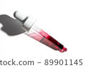 Liquid red oil serum drop in pipette isolated on white background. Retinol, aha acid, collagen skincare fluid, close up photo with shallow depth of field. Transparent crimson essence in dropper 89901145