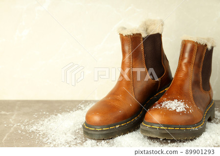 Boots with snow on gray textured table 89901293