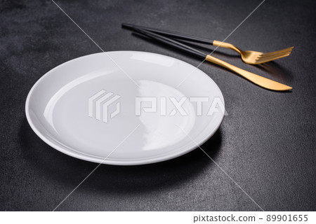 White plate on a black background. Flat lay, top view, copy space White plate on a black background. Flat lay, top view, copy space 89901655