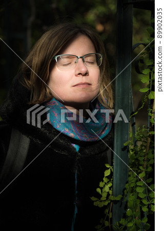 Portrait of an attractive thirty year old white woman with glasses, eyes closed 89902035