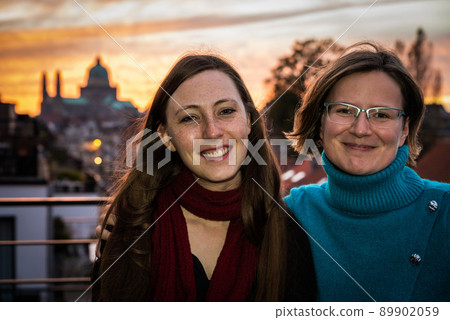 Jette, Brussels Capital Region - Belgium - 06 29 2020 Two girl friends, early thirties, smiling with a city background Jette, Brussels Capital Region - Belgium - 06 29 2020 Two girl friends, early thirties, smiling with a city background 89902059