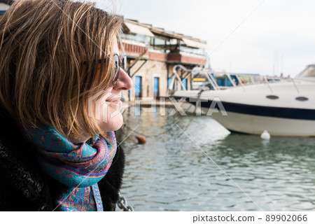 Freattyda, Athens - Greece - Happy thirty year old woman with sunglasses smiling on vacation with a yacht on the background Freattyda, Athens - Greece - Happy thirty year old woman with sunglasses smiling on vacation with a yacht on the background 89902066
