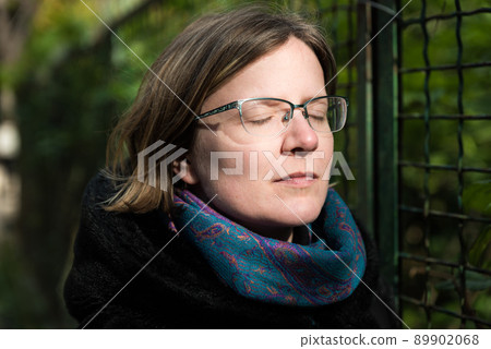 Portrait of an attractive thirty year old white woman with glasses, eyes closed 89902068
