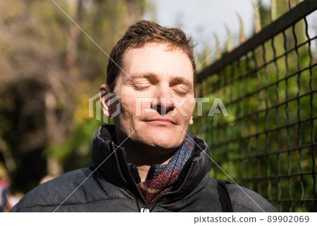 Portrait of a handsome forty year old man with glasses and winter clothes, eyes closed 89902069
