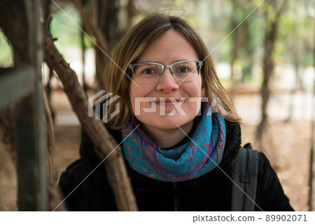 Portrait of an attractive thirty year old white woman with glasses smiling in a park background 89902071