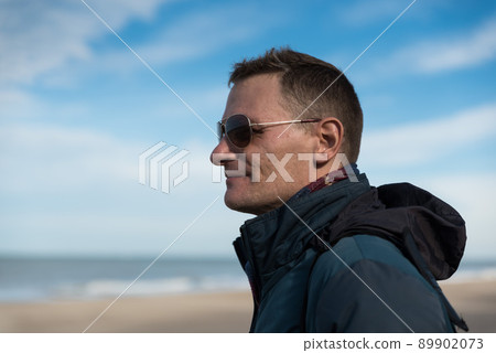 Ostend, West Flanders  Belgium, Attractive fourty year old man with blue jacket and sunglasses posing at the belgian seaside Ostend, West Flanders  Belgium, Attractive fourty year old man with blue jacket and sunglasses posing at the belgian seaside 89902073