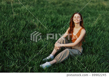 Lifestyle summer women on vacation in the park sitting on the green grass looking at the camera and smiling 89902245