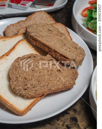 Sice of white and whole grain breads in the white plate. 89903007