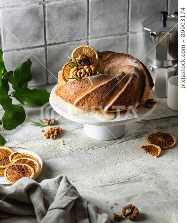 Bundt cake decorated with walnuts orange and icing. Bundt cake decorated with walnuts orange and icing. 89903174