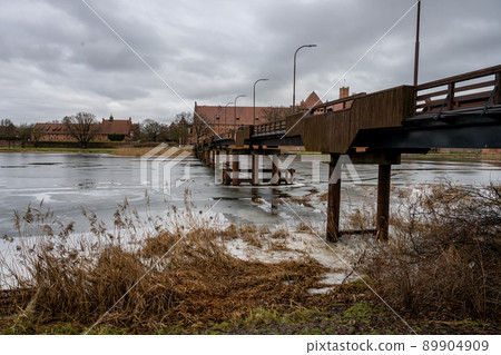 A bridge over the Nogat river with the Castle of the Teutonic Order in Malbork in the background. This is the largest castle in the world measured by land area and a UNESCO World Heritage Site A bridge over the Nogat river with the Castle of the Teutonic Order in Malbork in the background. This is the largest castle in the world measured by land area and a UNESCO World Heritage Site 89904909