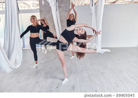 Group of fit women in sportwear stretching before fly yoga training in fitness club 89905045