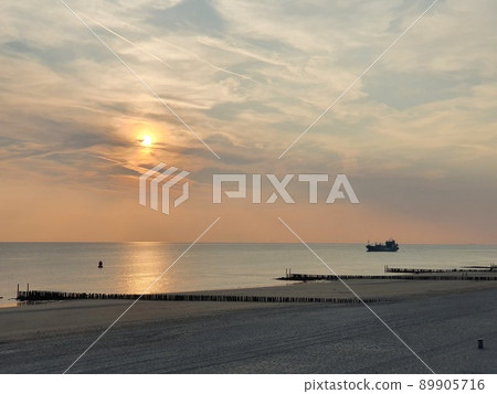 Sunset between clouds with a view over the beach till the sea Sunset between clouds with a view over the beach till the sea 89905716
