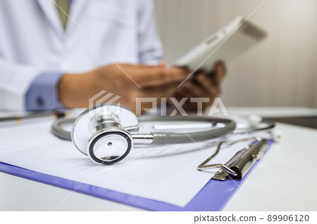 Close-up of stethoscope is lying on the clipboard in front of  a doctor. 89906120