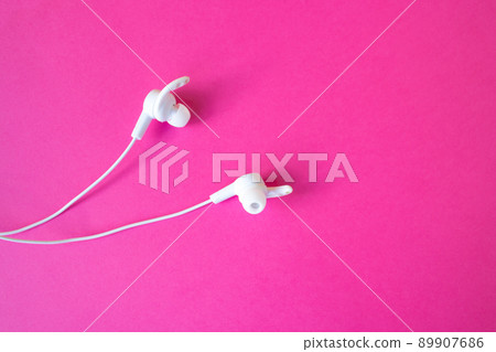White headphones with a wire on a pinkbackground. White headphones with a wire on a pinkbackground. 89907686