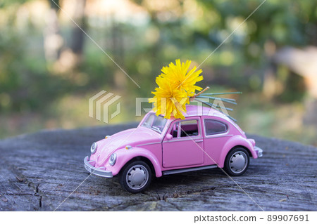 Toy pink car. Romantic postcard with a woman's car. Flower delivery concept 89907691