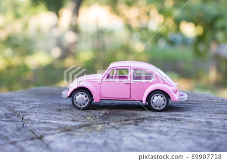 Pink toy car on a wooden stump 89907718