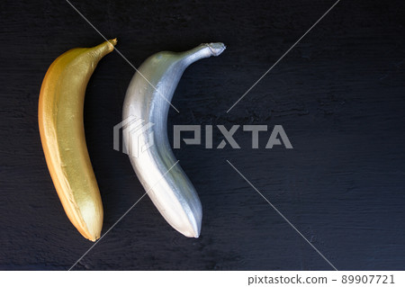 Golden and silver banana on a black background. Trend concept, horizontal frame Golden and silver banana on a black background. Trend concept, horizontal frame 89907721