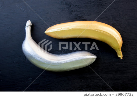 Golden and silver banana on a black background. Trend concept, horizontal frame Golden and silver banana on a black background. Trend concept, horizontal frame 89907722