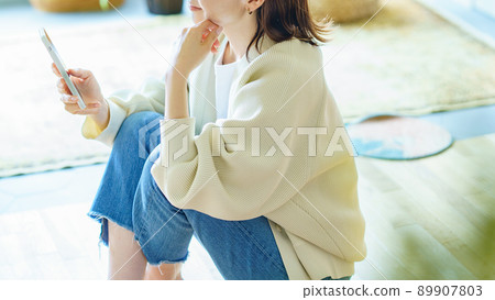 在房間裡拿著智能手機的女人 89907803