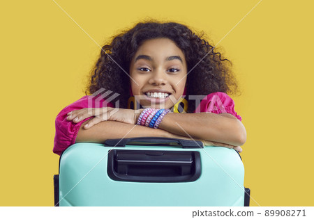Portrait of happy beautiful African American girl with travel bag on yellow studio background 89908271