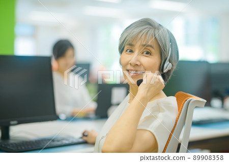 Senior female operator working in the office Senior female operator working in the office 89908358