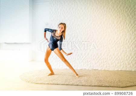 girl in sport bodysuit and ballet shoes making stretching exercise 89908726