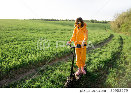 Person rides electric scooter on green field Person rides electric scooter on green field 89908979