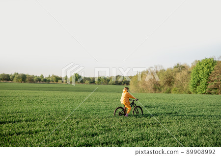 Woman rides a bicycle on a field Woman rides a bicycle on a field 89908992
