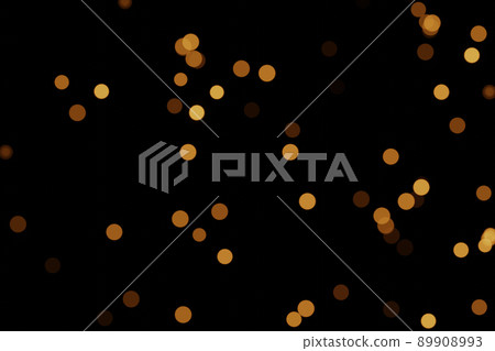 Defocused bokeh lights on black background, an abstract naturally blurred backdrop for Christmas eve or birthday party. Festive light texture. Yellow and red garland in blur. Overlay effect for design 89908993