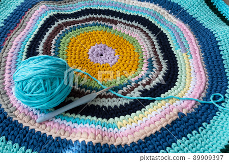 A rug made of knitted yarn and a crochet hook. Home needlework. A rug made of knitted yarn and a crochet hook. Home needlework. 89909397