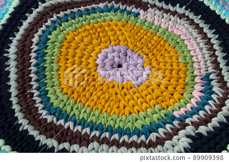 The mat is made of knitted yarn, hand-knitted on knitting needles. Home needlework. The mat is made of knitted yarn, hand-knitted on knitting needles. Home needlework. 89909398